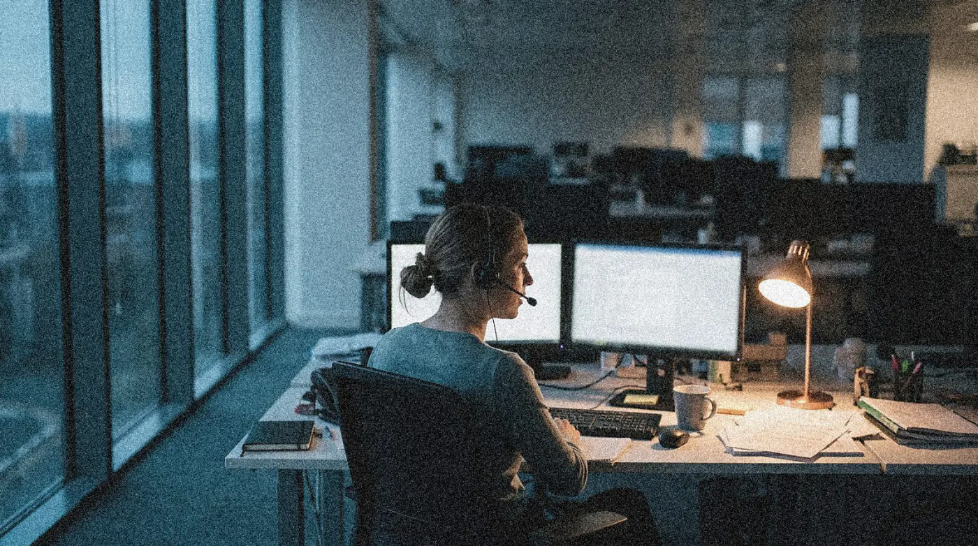 A headset beside a monitor showing a support ticket queue